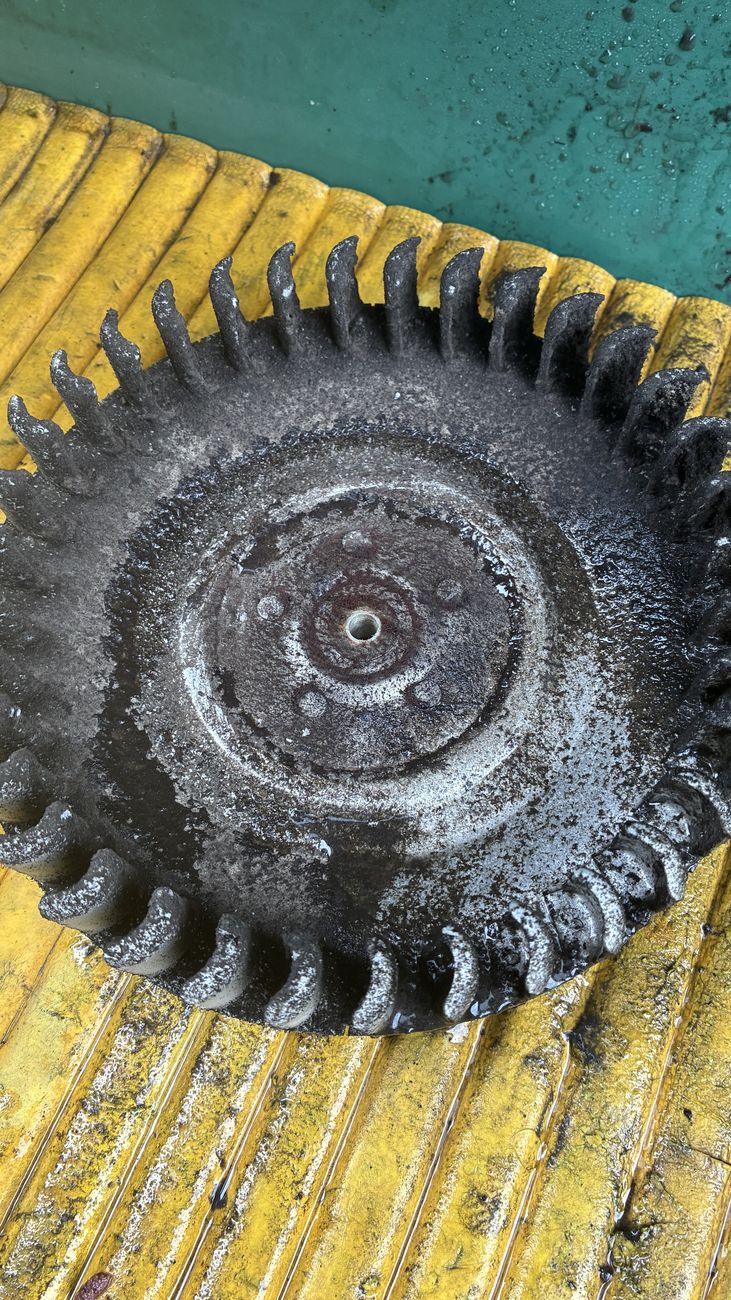 取り外した換気扇のファン。羽根全体が黒い汚れの層で覆われている